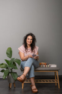 שני יושבת על ספסל עם קלפים ביד ותמציות פרחי באך ליד